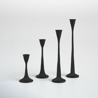 four black candlesticks of different heights in a line
