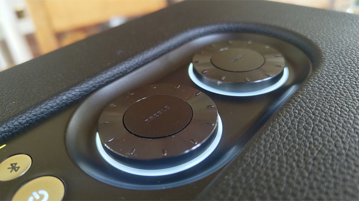 A close-up of the top of a JBL Authentics 300 wireless speaker. It shows two circular dials and two buttons (one for power, the other to control Bluetooth).