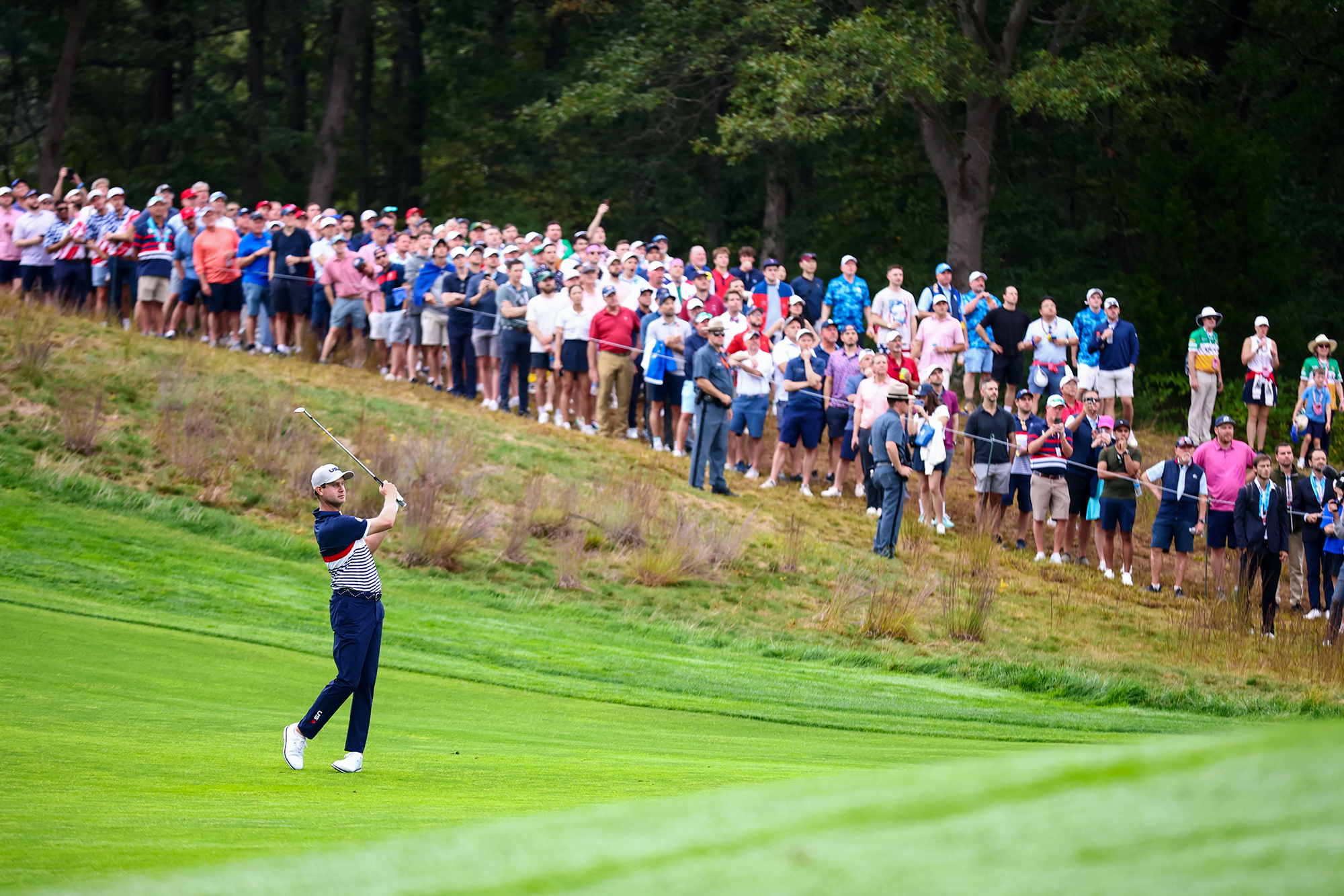 Harris English hitting an iron shot at the Ryder Cup during Friday foursomes in front of a gallery of fans