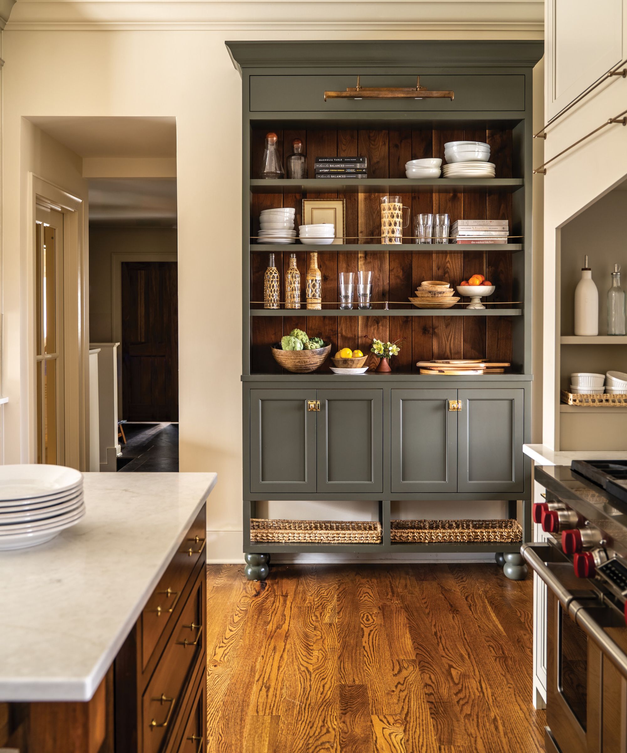 A kitchen with white walls, a wooden island, and a green freestanding unit with open shelving