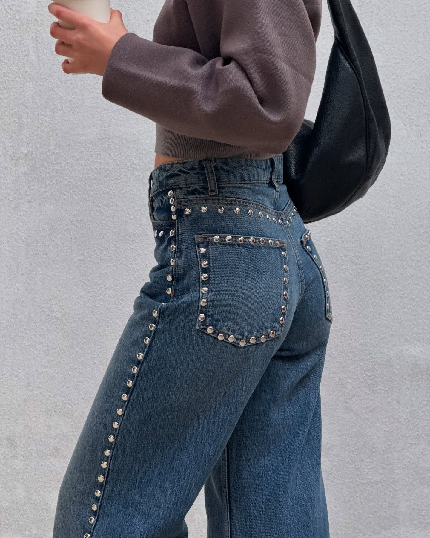 Influencer @tamaramory wears stud-embellished jeans with a brown cardigan and black bag.