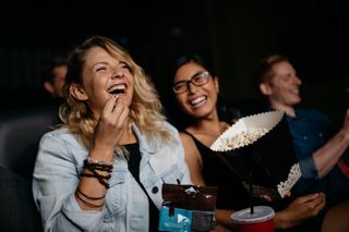 Woman laughing at movie theater with bowl of popcorn