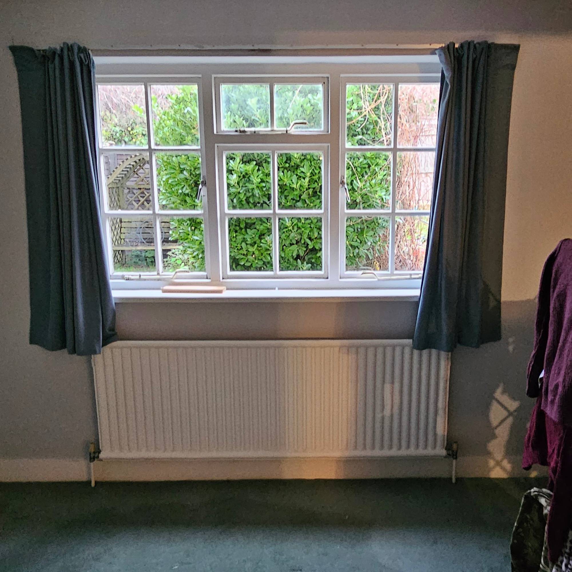 white cottage windows with blue curtains above radiator