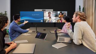 Four people in a meeting room video conferencing with four remote participants.