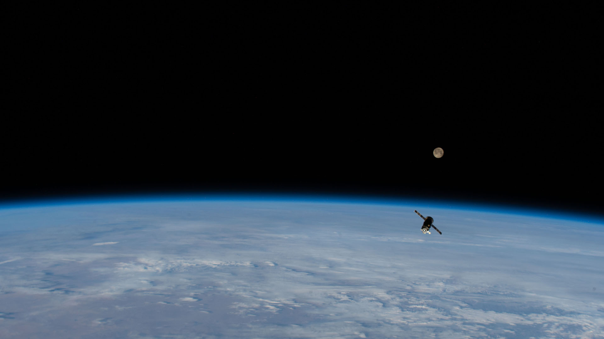 The full moon above the Earth's horizon along with resupply ship.