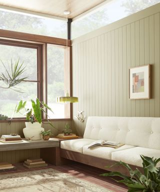 A light gray-green sunroom with a white sofa and expansive windows