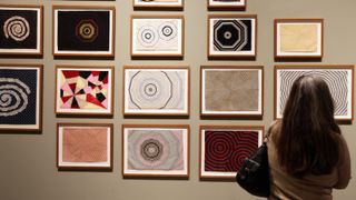 A woman looks at embroidered art in a gallery