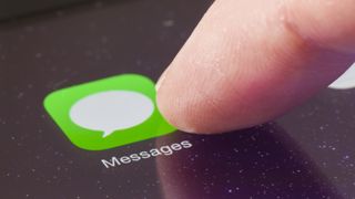 iOS message icon with a fingertip tapping it, representing an article about how to stop spam texts on iPhone using message filtering