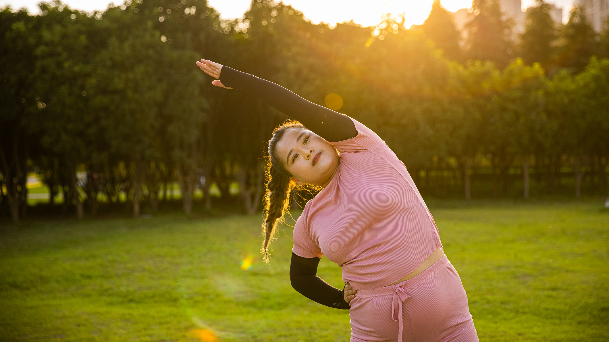 Woman stretches to the side in a park