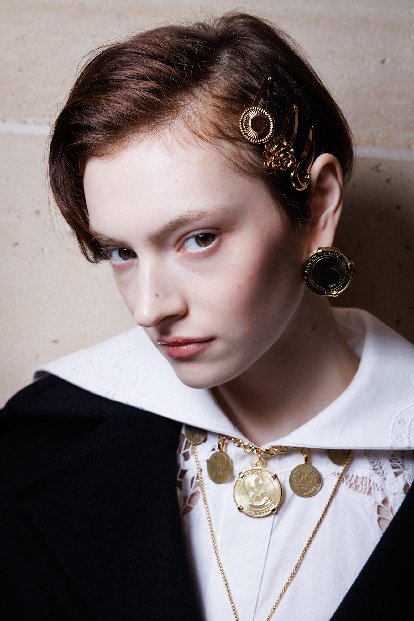 model with short dark brunette hair wearing three decorative gold snap clips on one side of hair