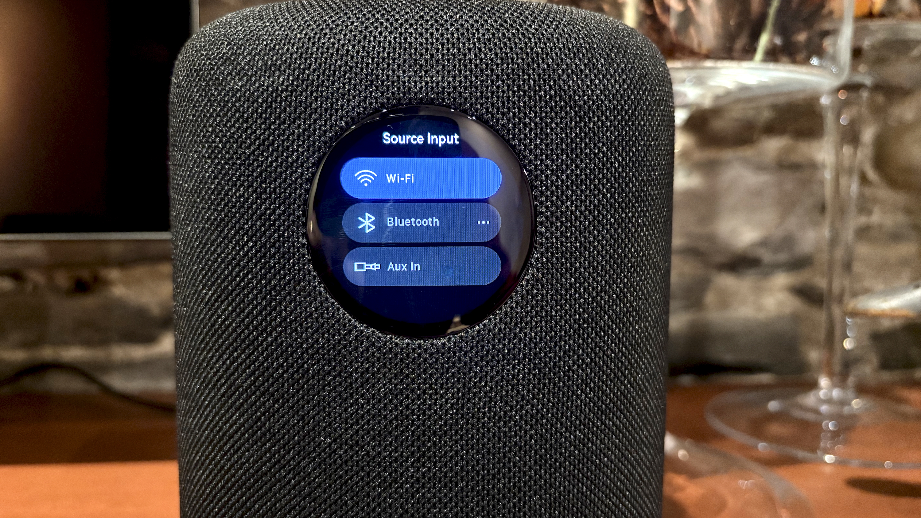 The WiiM Sound, in a home, on a varnished wooden table, showing the illuminated front panel 