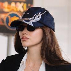 Dove Cameron wearing a black coat, white tank top, black track pants, and puma sneakers