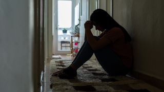 Sad woman sitting corridor floor