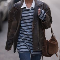 woman wearing striped rugby shirt, leather jacket, and suede bag