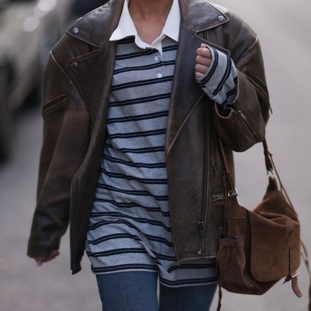woman wearing striped rugby shirt, leather jacket, and suede bag 