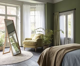 Bedroom with olvie green walls, shutters and sheer curtains