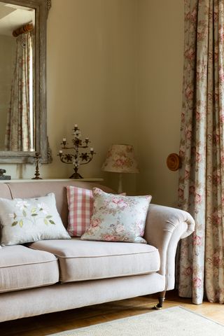 Living room with traditional beige sofa with scroll arms and floral curtains