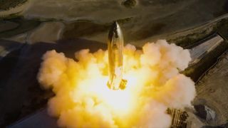 silver spacex starship with fiery exhaust from engines on test stand