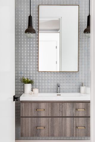 gray bathroom with grey square tiles, wooden wall mounted vanity, mirror, pendants
