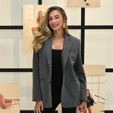 Zara McDermott smiling in a black jumpsuit with a grey blazer on top