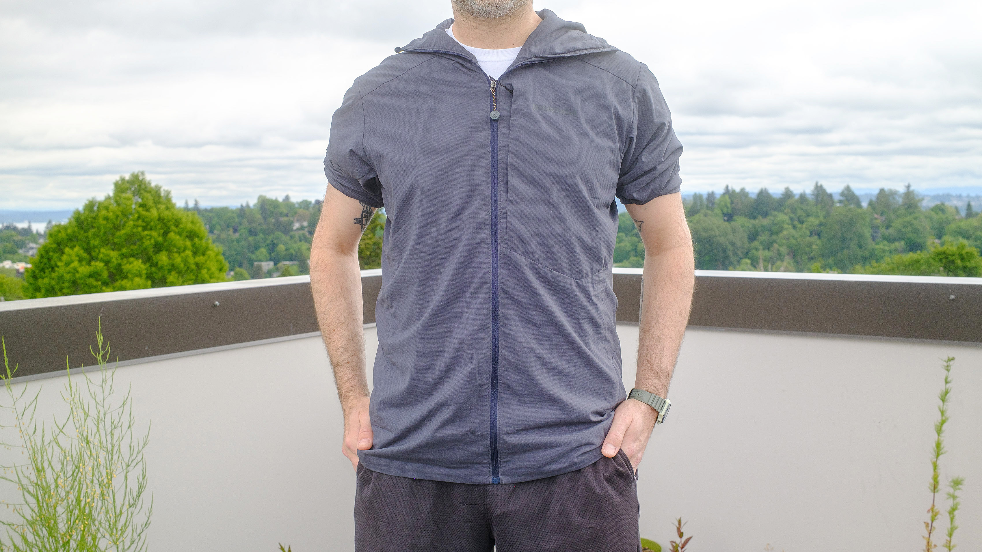 Senior writer Dan Bracaglia wearing the Patagonia Nano-Air Ultralight in grey/blue on the roof of his home in Seattle, Washington with trees and overcast skies in the distance