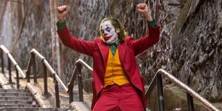 Joaquin Phoenix in Todd Phillips Joker, dancing in red suit and clown makeup