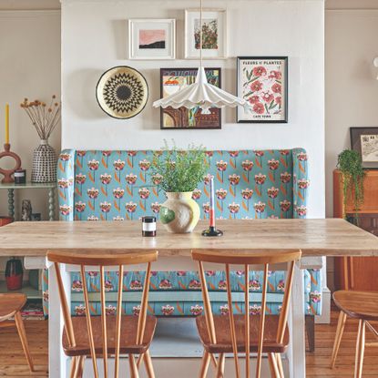 A dining area with a patterned banquette seating and a pleated pendant light hung above the dining table