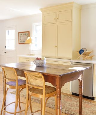 A butter yellow kitchen with a wooden kitchen freestanding island