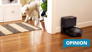 The iRobot Roomba J7+ in a hall while a man and a dog enter the home