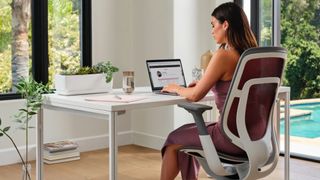 A person sitting in a Steelcase chair at a desk