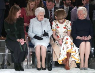 Queen Elizabeth II sits with Anna Wintour, Caroline Rush (L), chief executive of the British Fashion Council (BFC) and royal dressmaker Angela Kelly (R) as they view Richard Quinn's runway show before presenting him with the inaugural Queen Elizabeth II Award for British Design as she visits London Fashion Week's BFC Show Space on February 20, 2018 in London, United Kingdom