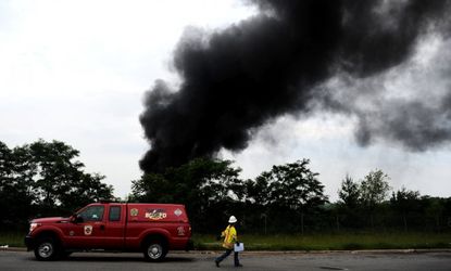 A worker walks by as smoke billows from a train derailment that caused a major explosion in Baltimore on May 28.