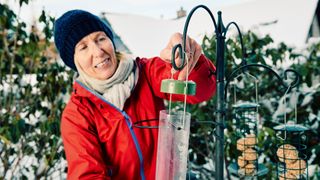 Woman hanging bird feeder outside