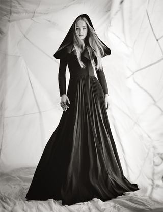 Black and white image of a model wearing a black, hooded dress