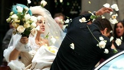Angry Sarah Jessica Parker in wedding gown hitting groom with flower bouquet