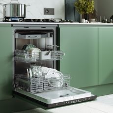 Stacked dishwasher with open door in kitchen with green cabinets and a pot on the hob