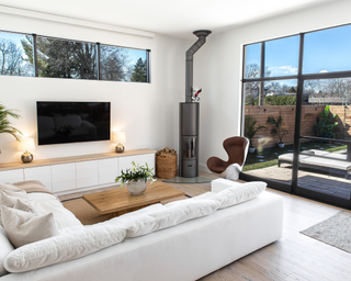 White living room with sectional, wooden coffee table and television with house plant