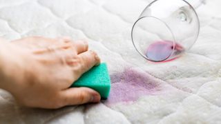 Close-Up Of Hand Cleaning Wine Stain On Mattress At Home