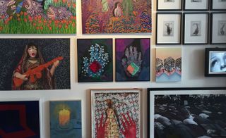 A variety of different sized and types of paintings on a wall.