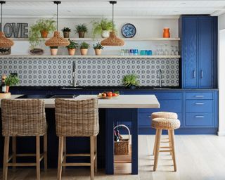Blue kitchen scheme with blue island and cabinets and patterned blue tiled backsplash, and woven materials bar stools