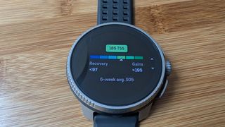 Suunto Race on a bamboo table showing the TSS score screen.