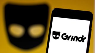The Grindr app on a smartphone in front of a background of its logo