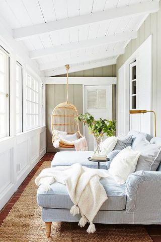White sunroom with blue couch and hanging chair