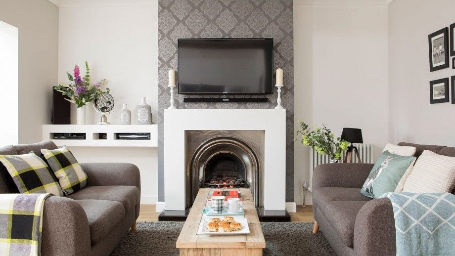 living room with white walls wallpaper and grey sofa.