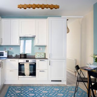 white kitchen with blue walls and blue geometric rug