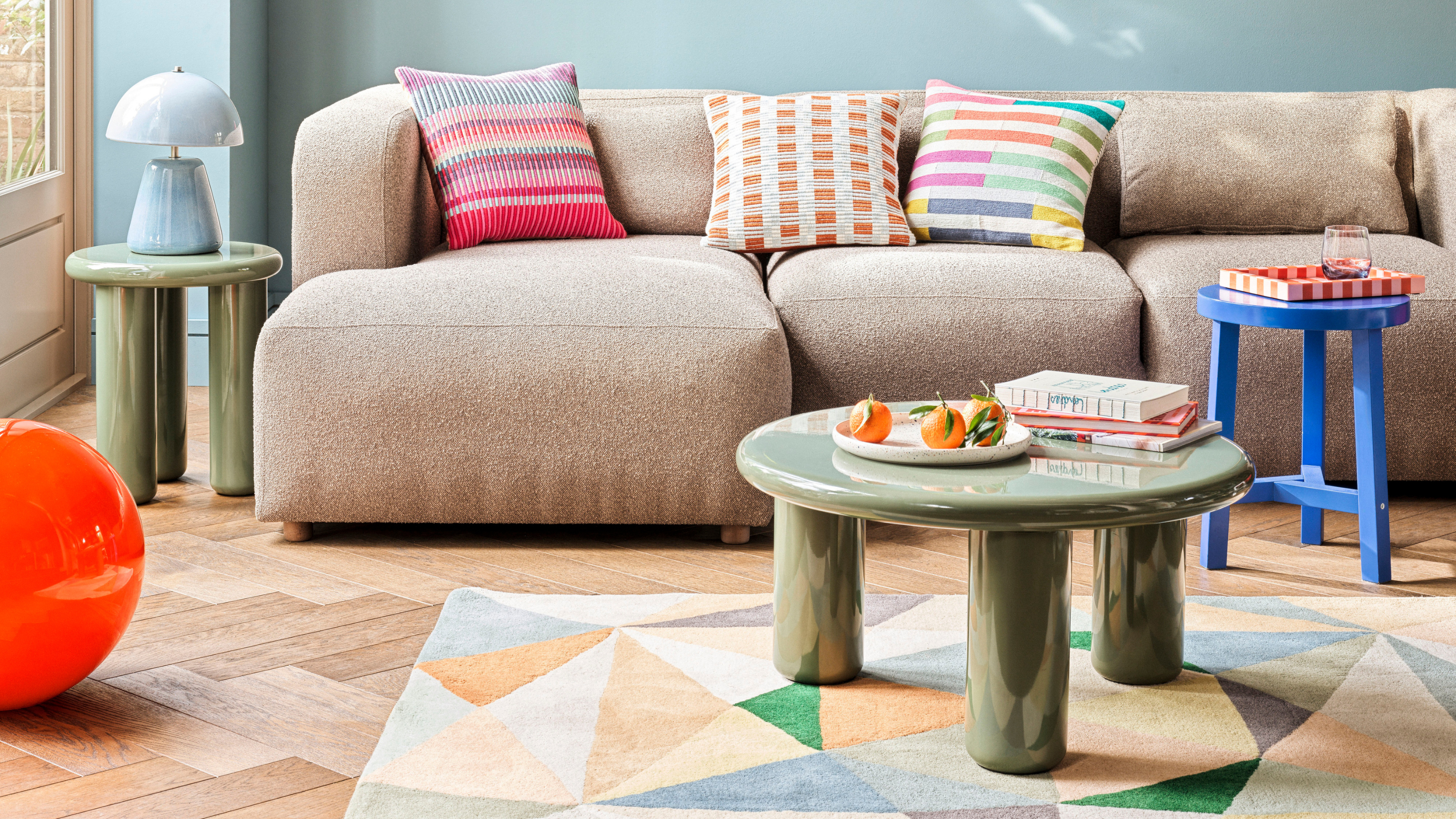 Habitat Geometric Patch Wool Cut Pile Rug in a sky blue lving room. There is an XL Calliban light in orange, beige sofa and green lacquered coffee table.