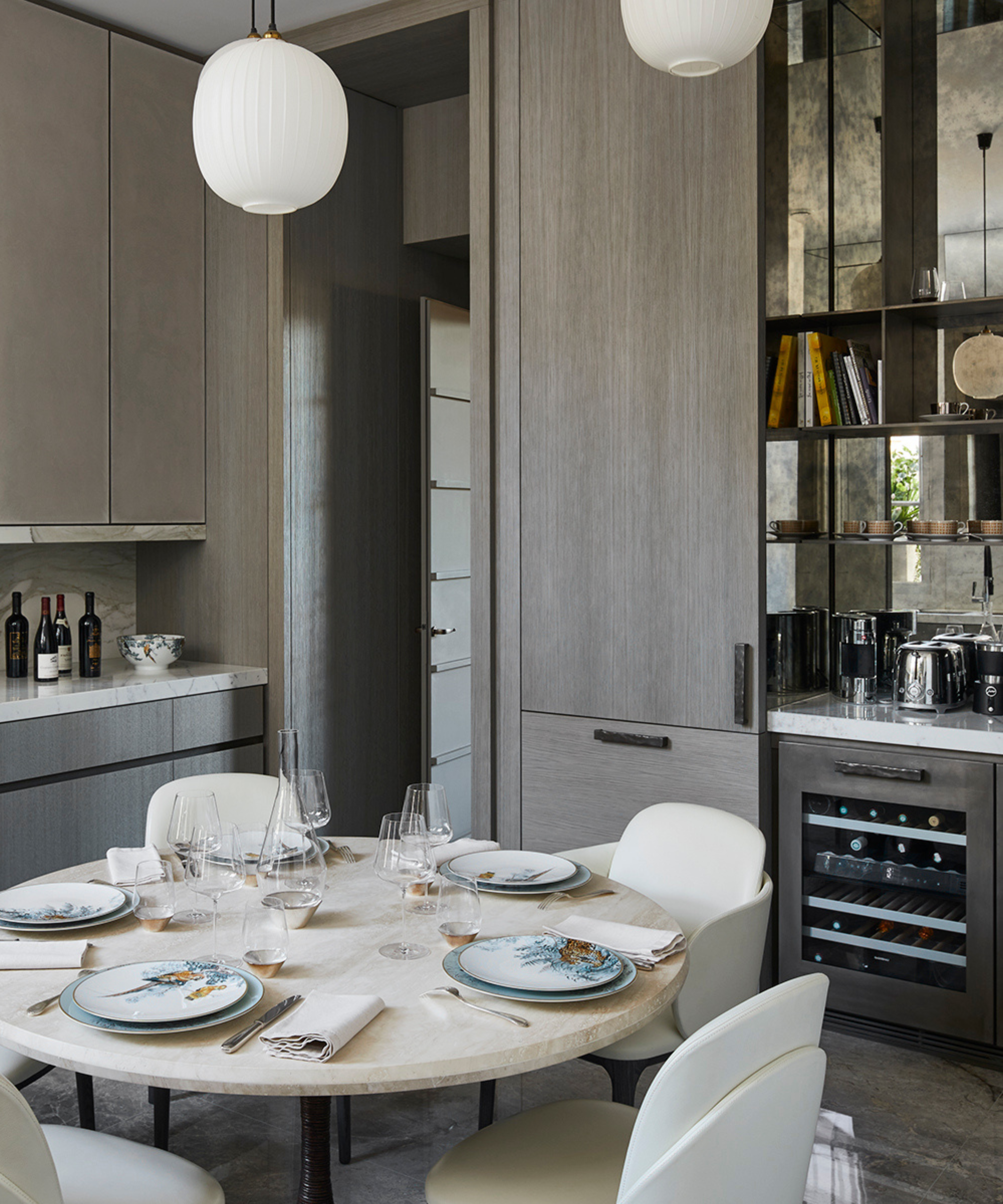 Gray kitchen with large white pendant lighting, mirror detail and central dining table