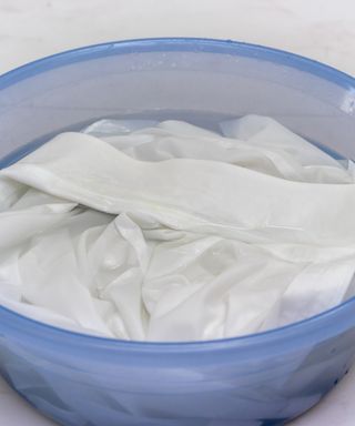 An image of a blue bowl with cloths soaking in it