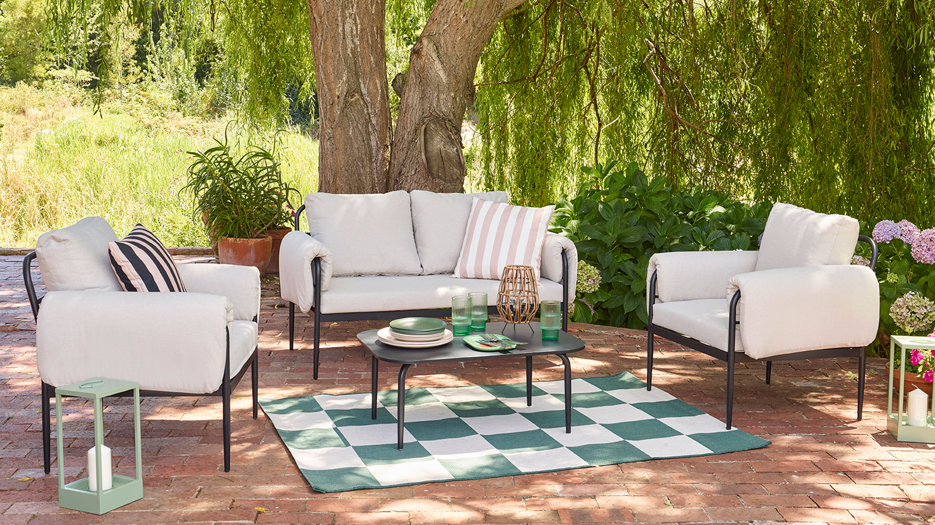 A white sofa set layered with stripe cushions and a check rug