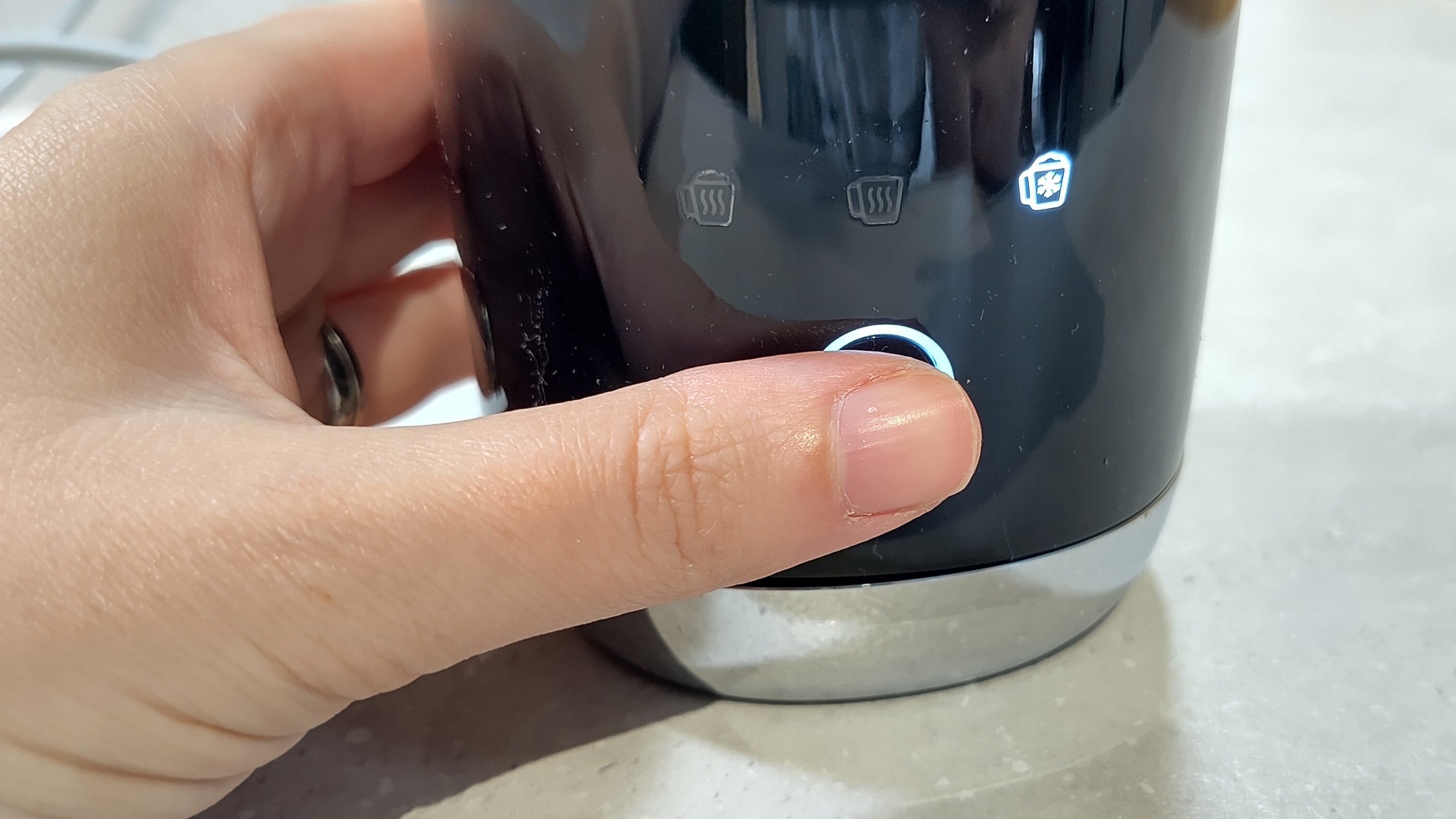 Person pressing button on Smeg milk frother